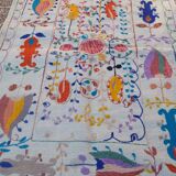 White suzani kilim rug with embroidered colorful patterns