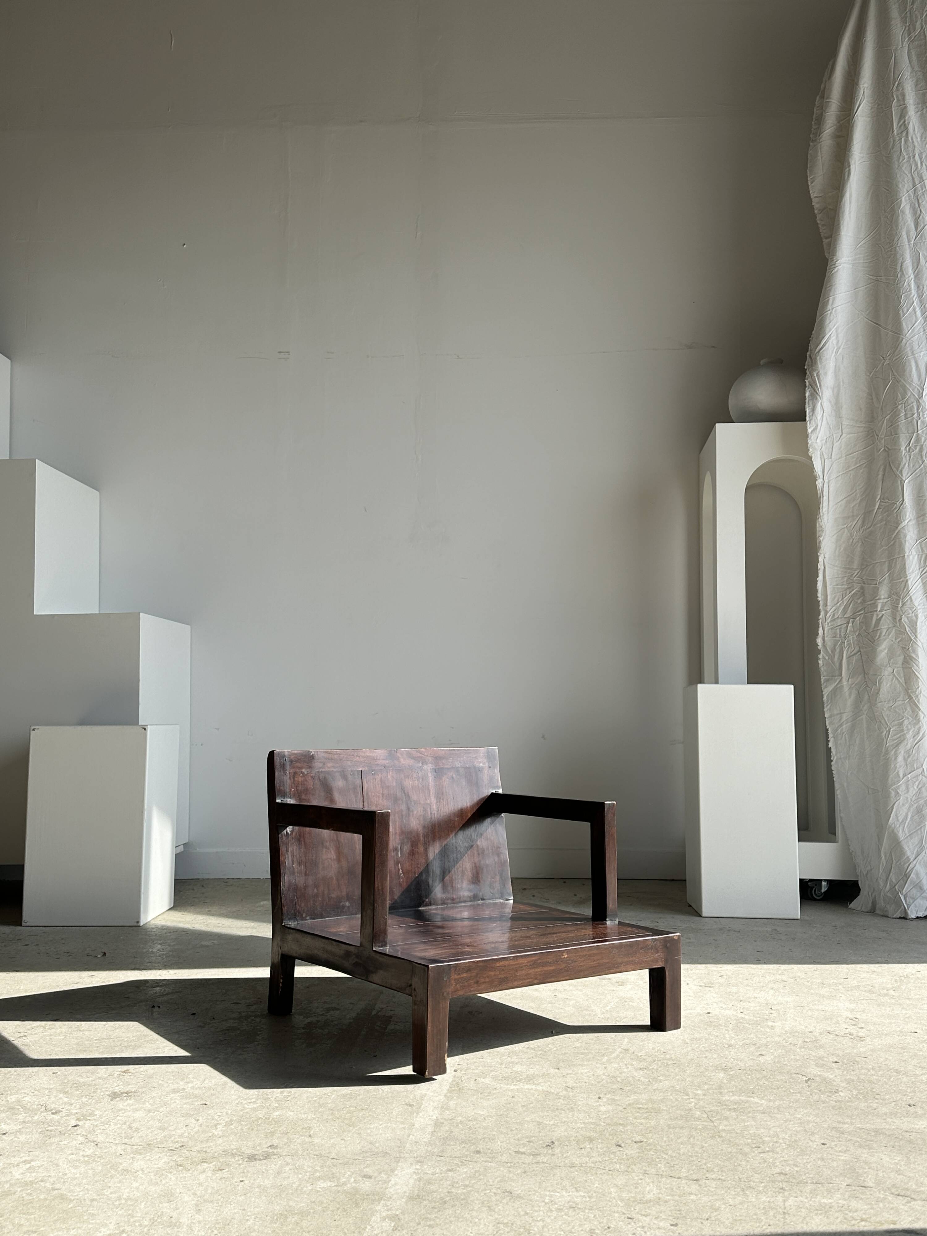 Small low armchair in varnished brown wood