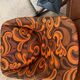 Vintage space age swivel chair with psychedelic pattern in shades of orange.
