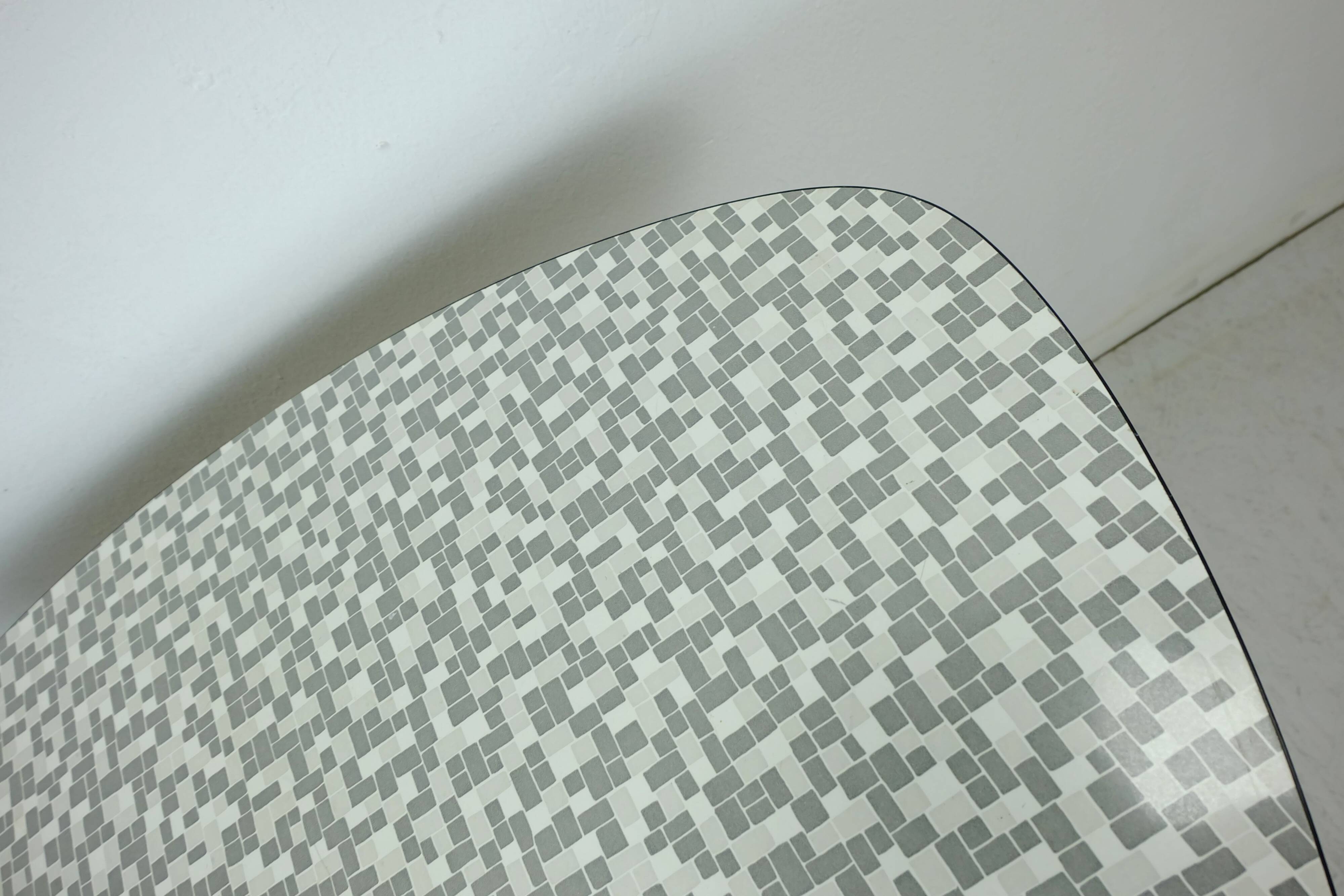 Table basse des années 1950 à trois pieds avec un plateau en formica et des pieds en chrome inclinés.