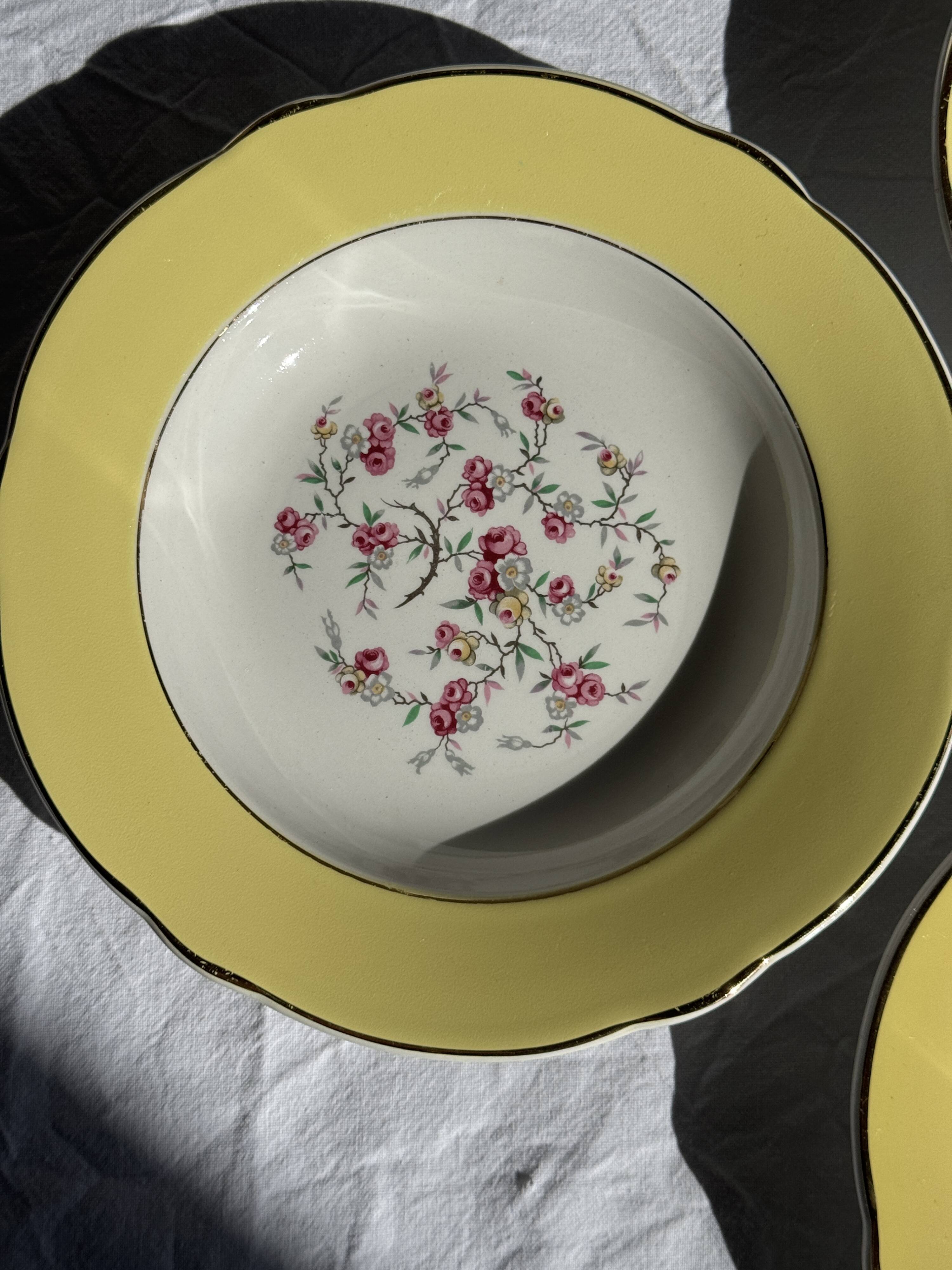 Set of 9 large vintage yellow deep plates with pink flowers and a gold rim.
