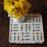 Vintage laminated wooden trivet with yellow, green, and blue flowers