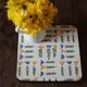 Vintage laminated wooden trivet with yellow, green, and blue flowers