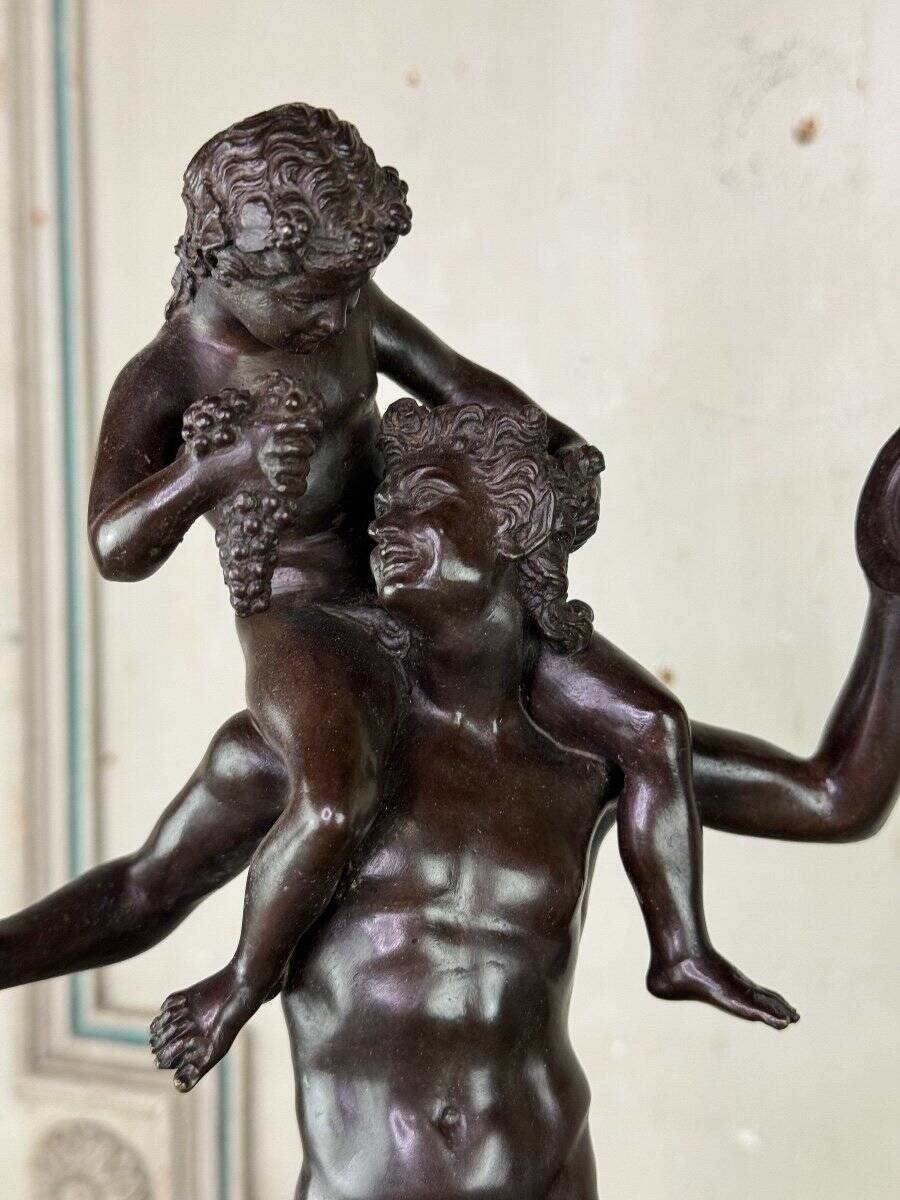 Dionysus on the shoulders of a satyr, bronze after the antique on a yellow Siena base.
