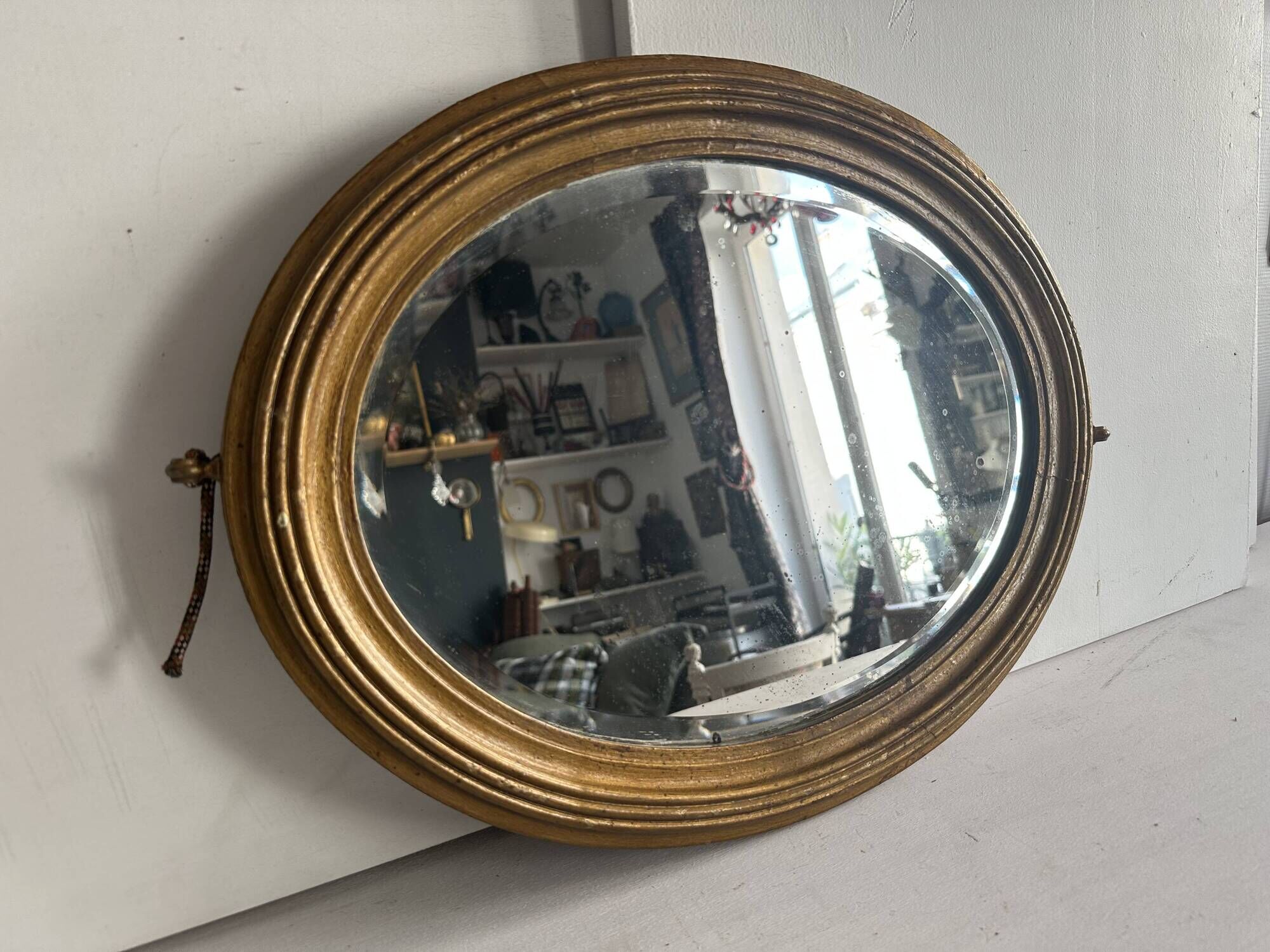 Antique oval mirror in gilded wood, bevelled mercury glass, 19th century.