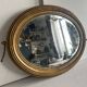 Antique oval mirror in gilded wood, bevelled mercury glass, 19th century.