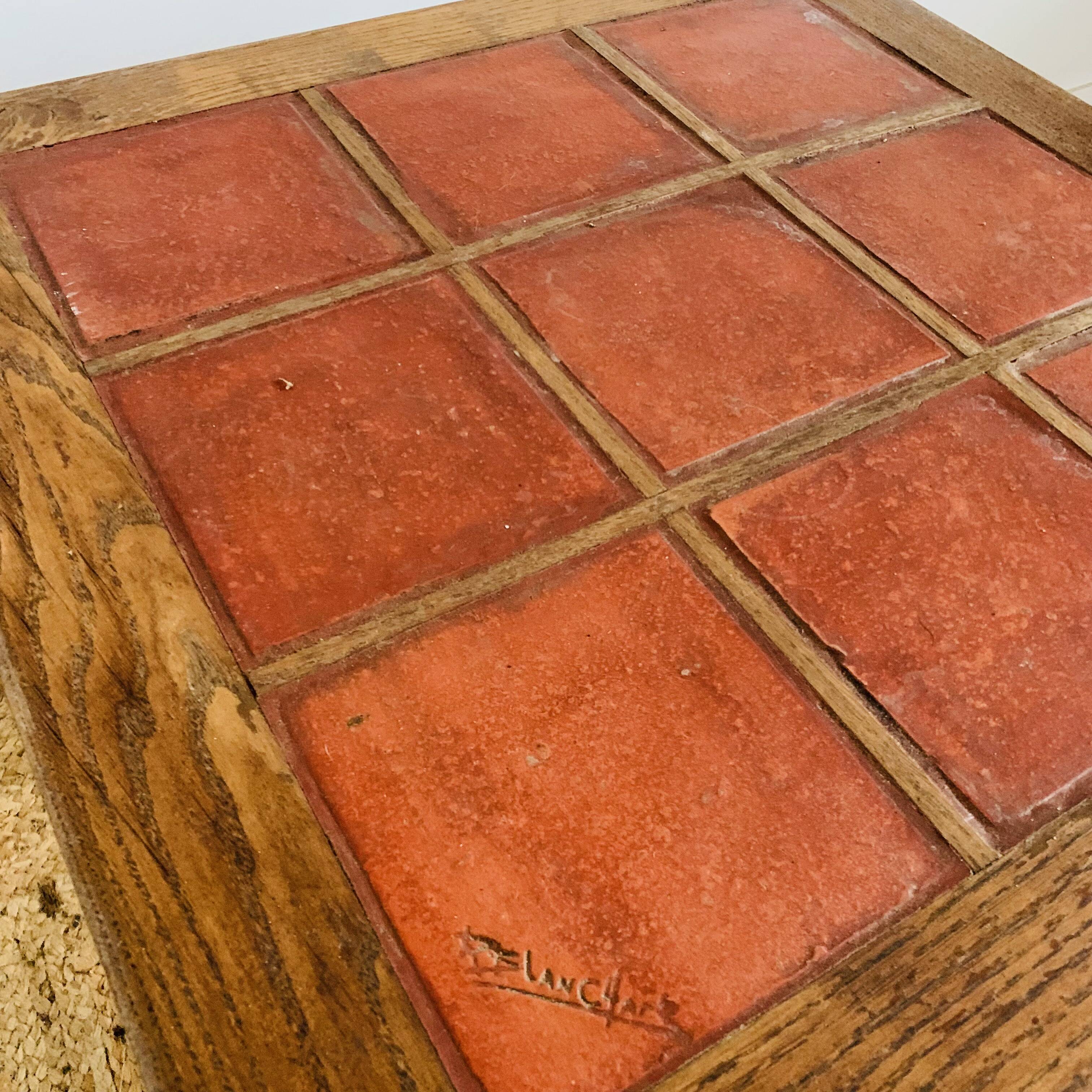 Square table with red tiles signed.