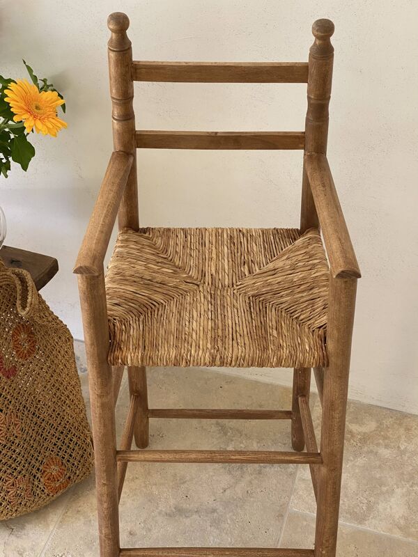 Ancienne chaise haute d’enfant en bois massif avec assise paillée.