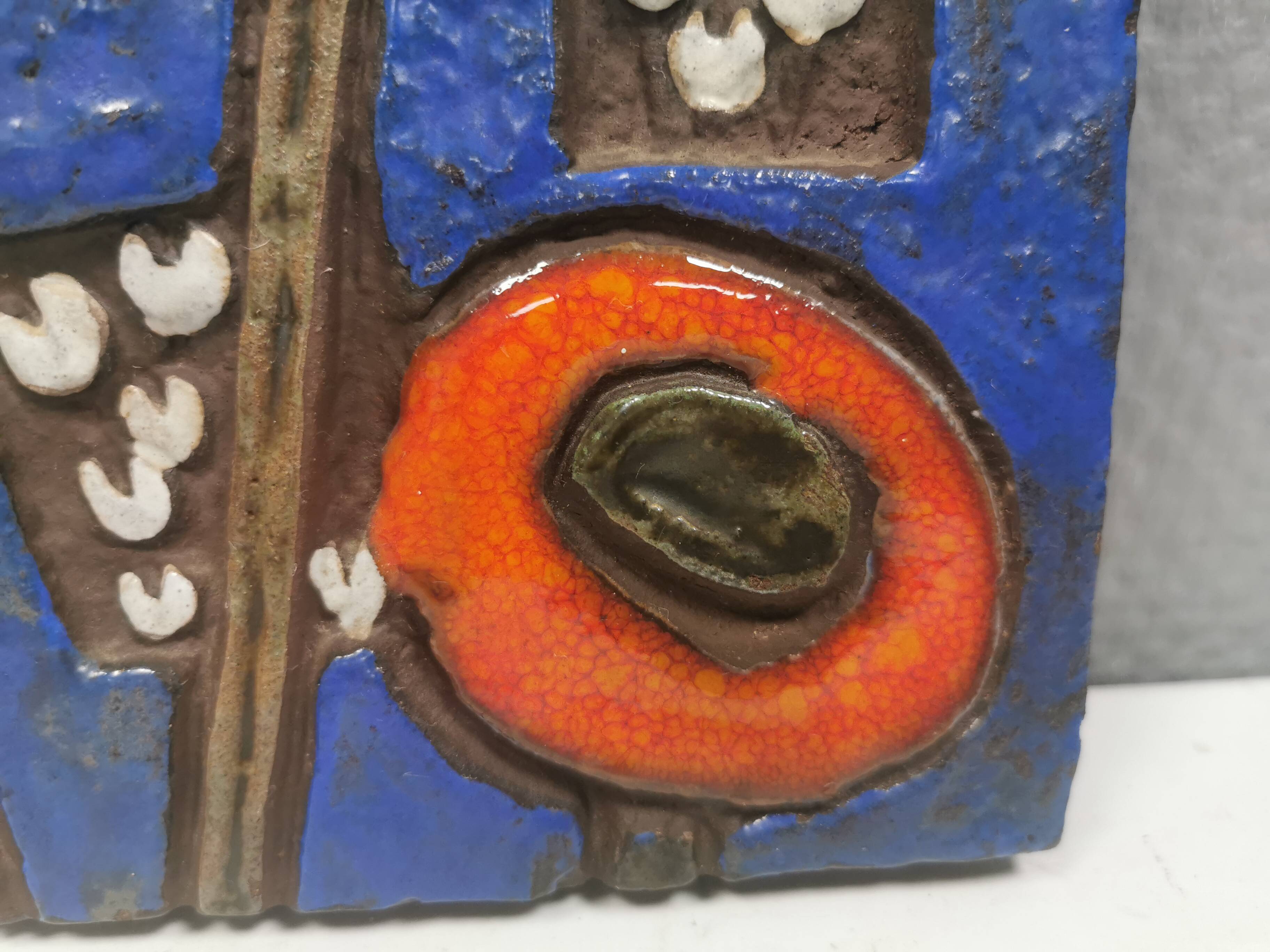 Ceramic relief in attractive blue with a motif of white/red flowers.