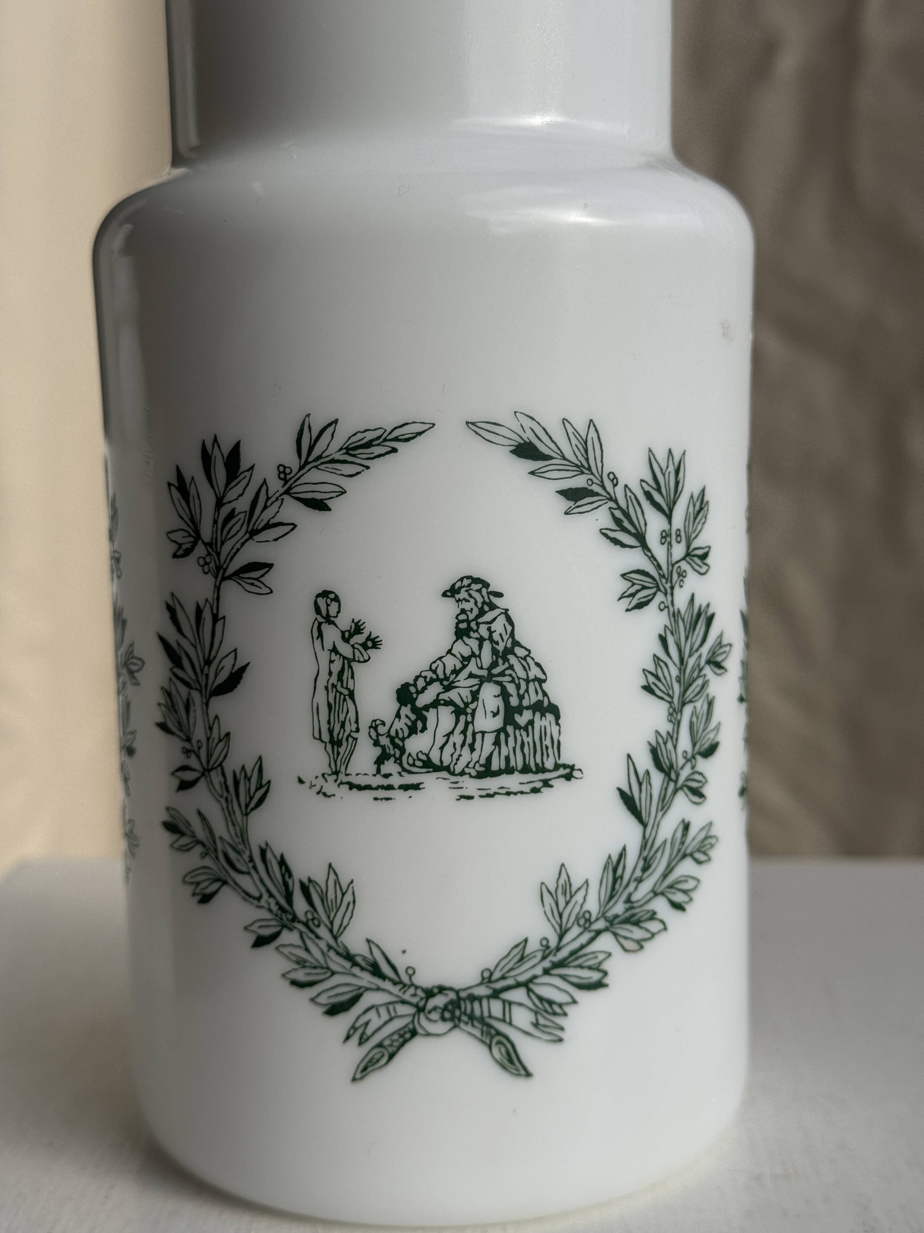 A pair of white glass bottles with Italian green patterns.