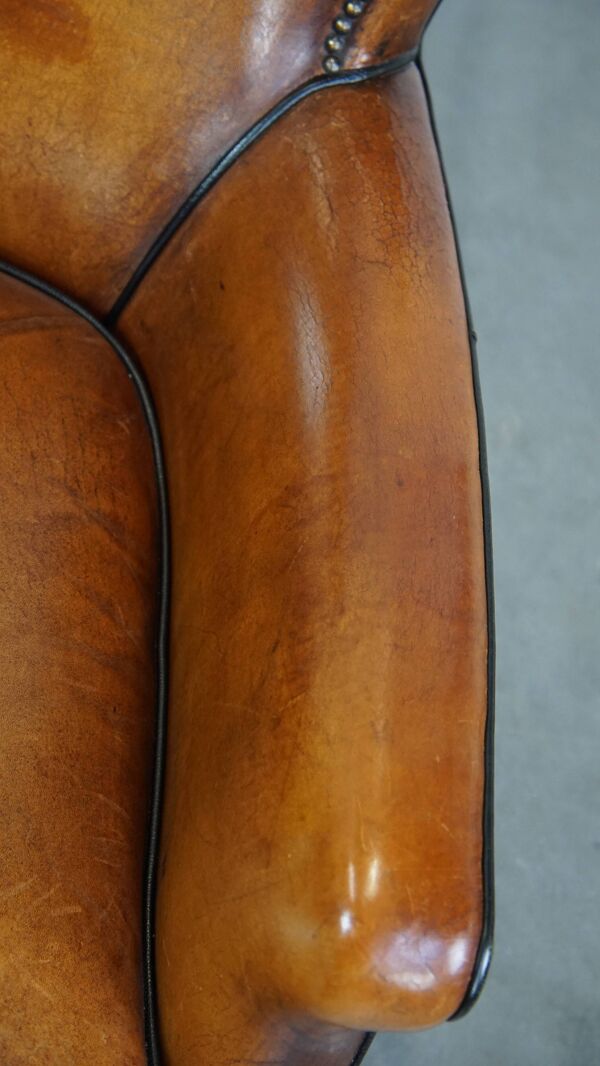 Fauteuil en peau de mouton couleur cognac avec passepoil noir et clous décoratifs