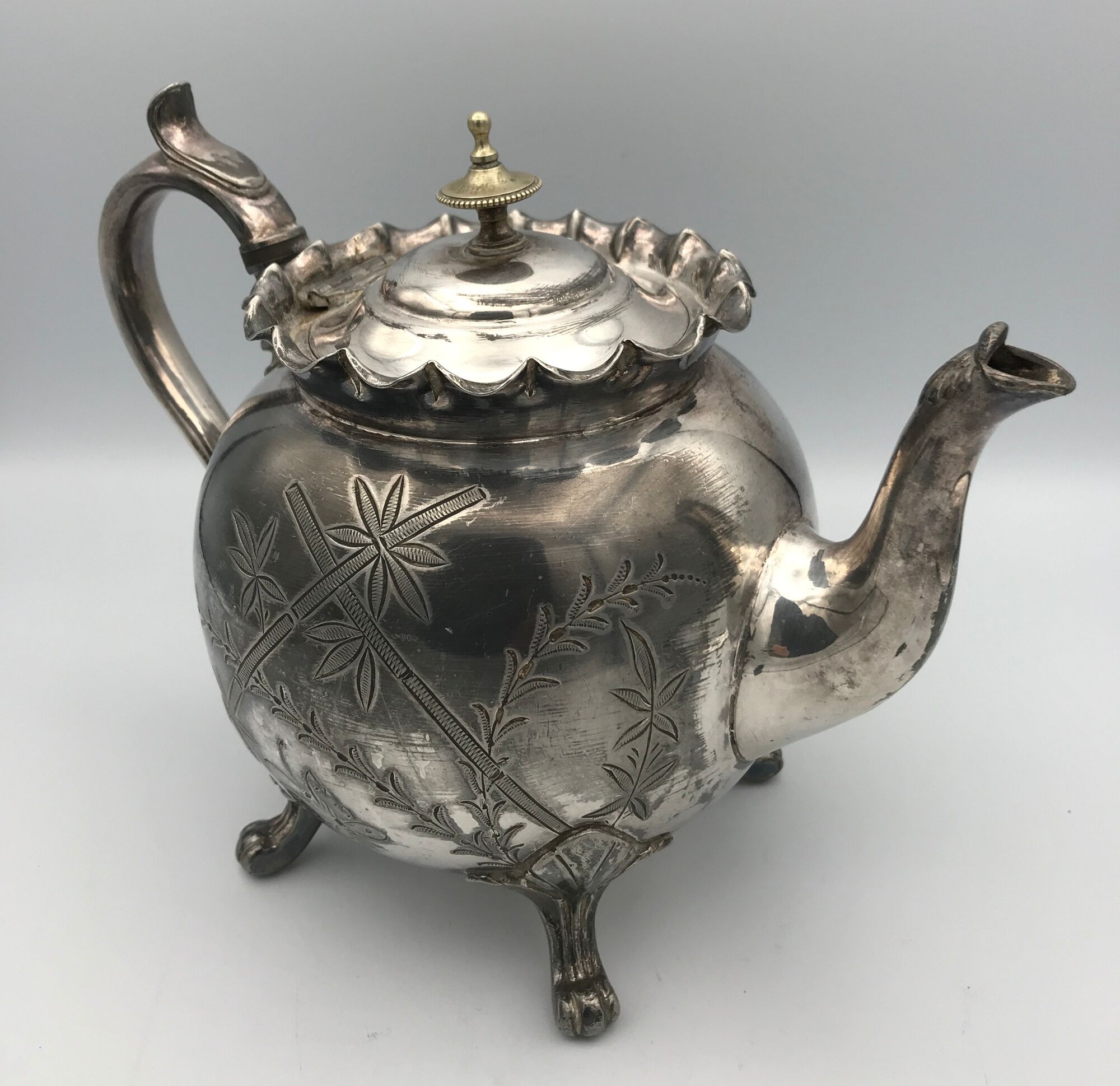 Old teapot pourer in silver metal decorated with foliage and butterflies