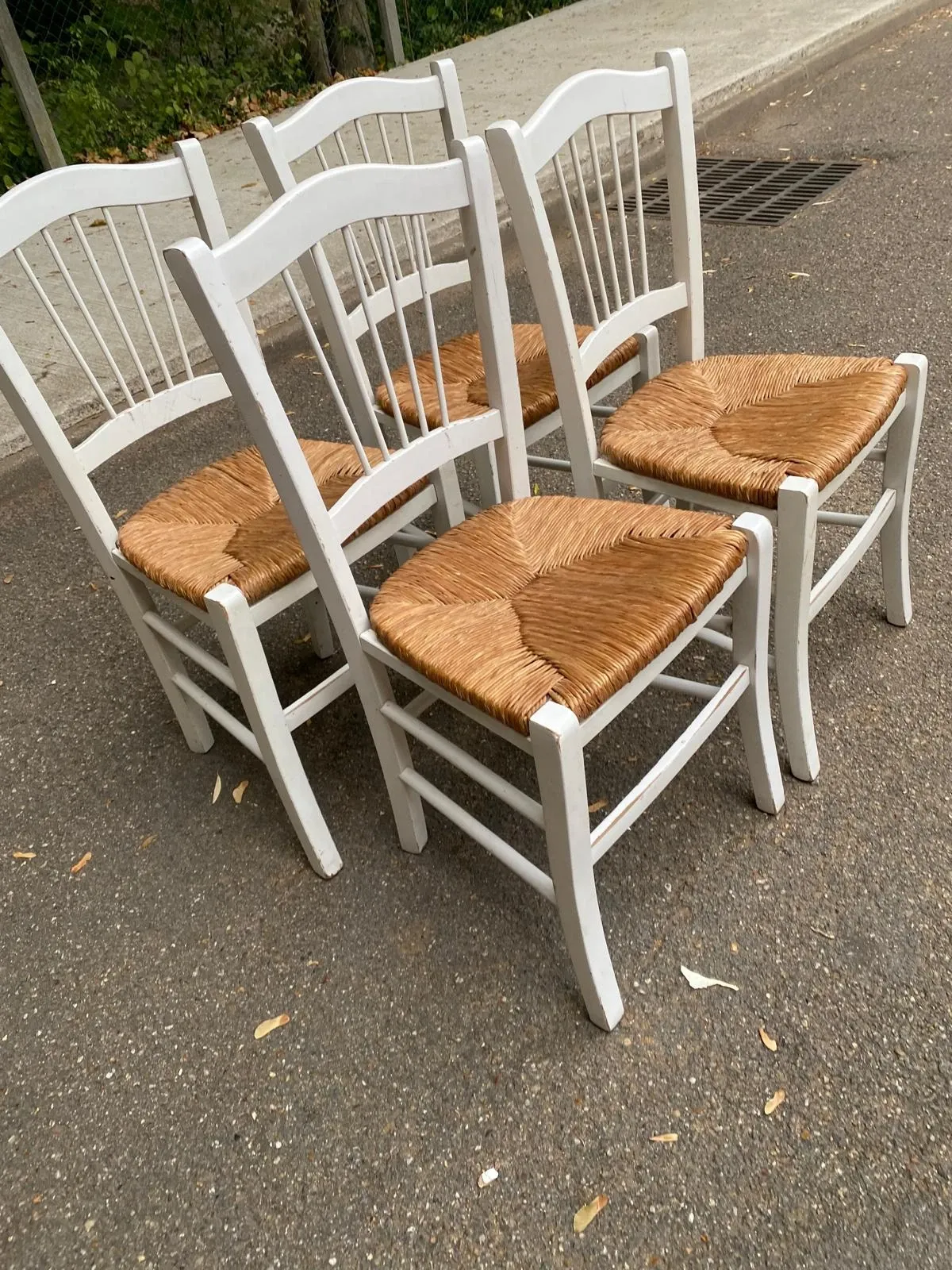Set of 4 rustic white wooden chairs with straw seats.
