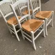 Set of 4 rustic white wooden chairs with straw seats.