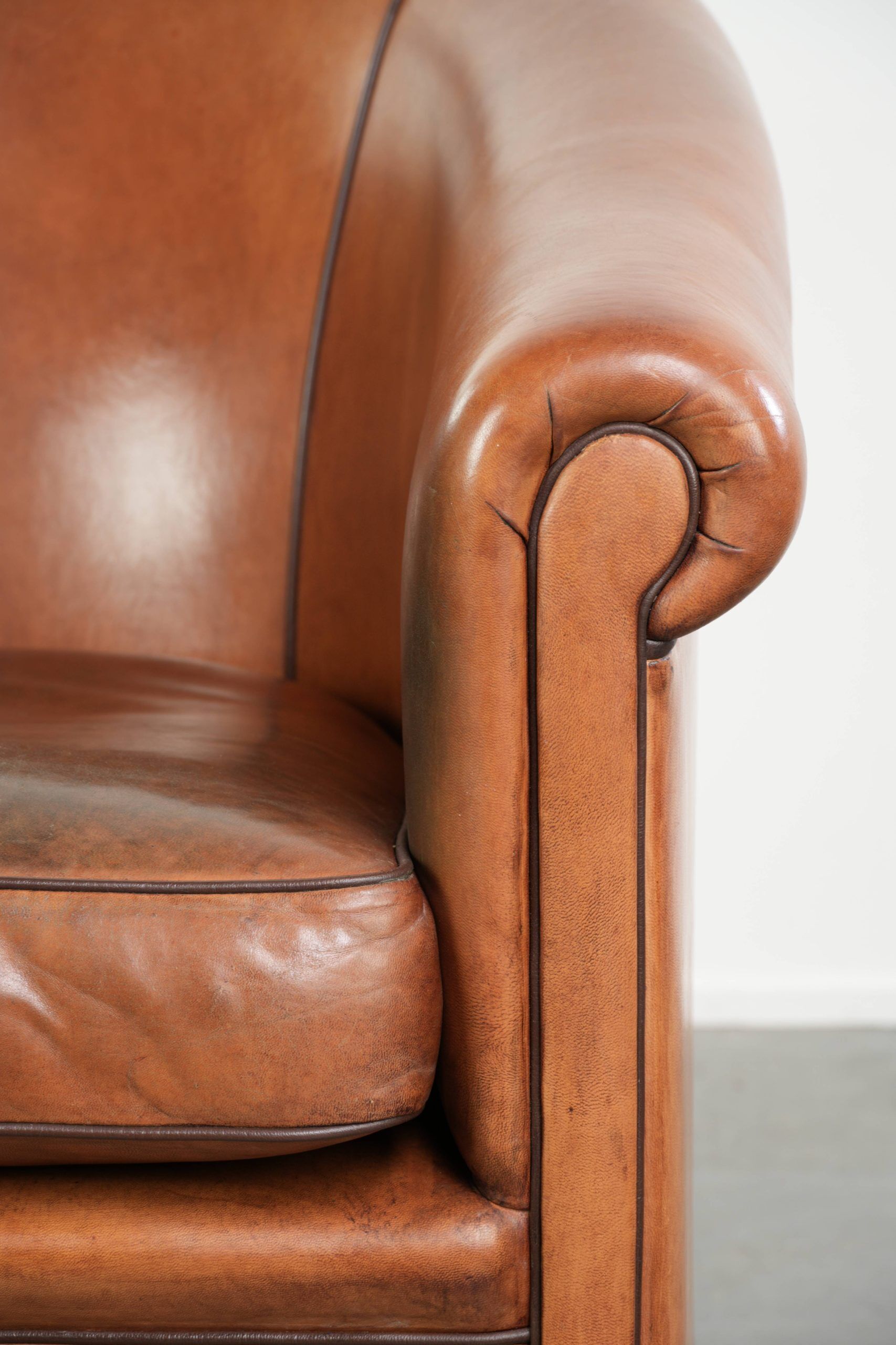 Vintage sheepskin club armchair with a warm colour scheme with black piping