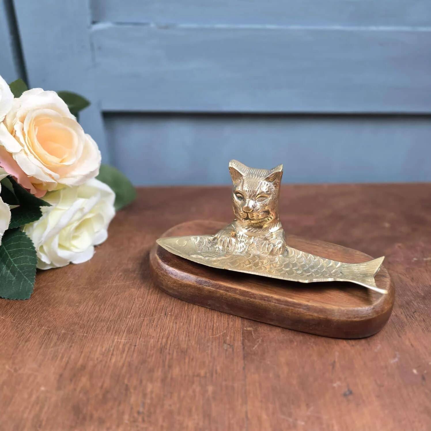 Vintage cat fish catchall in brass on a solid wood base.