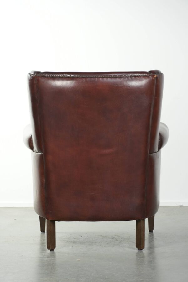 Fauteuil en peau de mouton vintage avec un dossier haut fini avec des clous décoratifs.