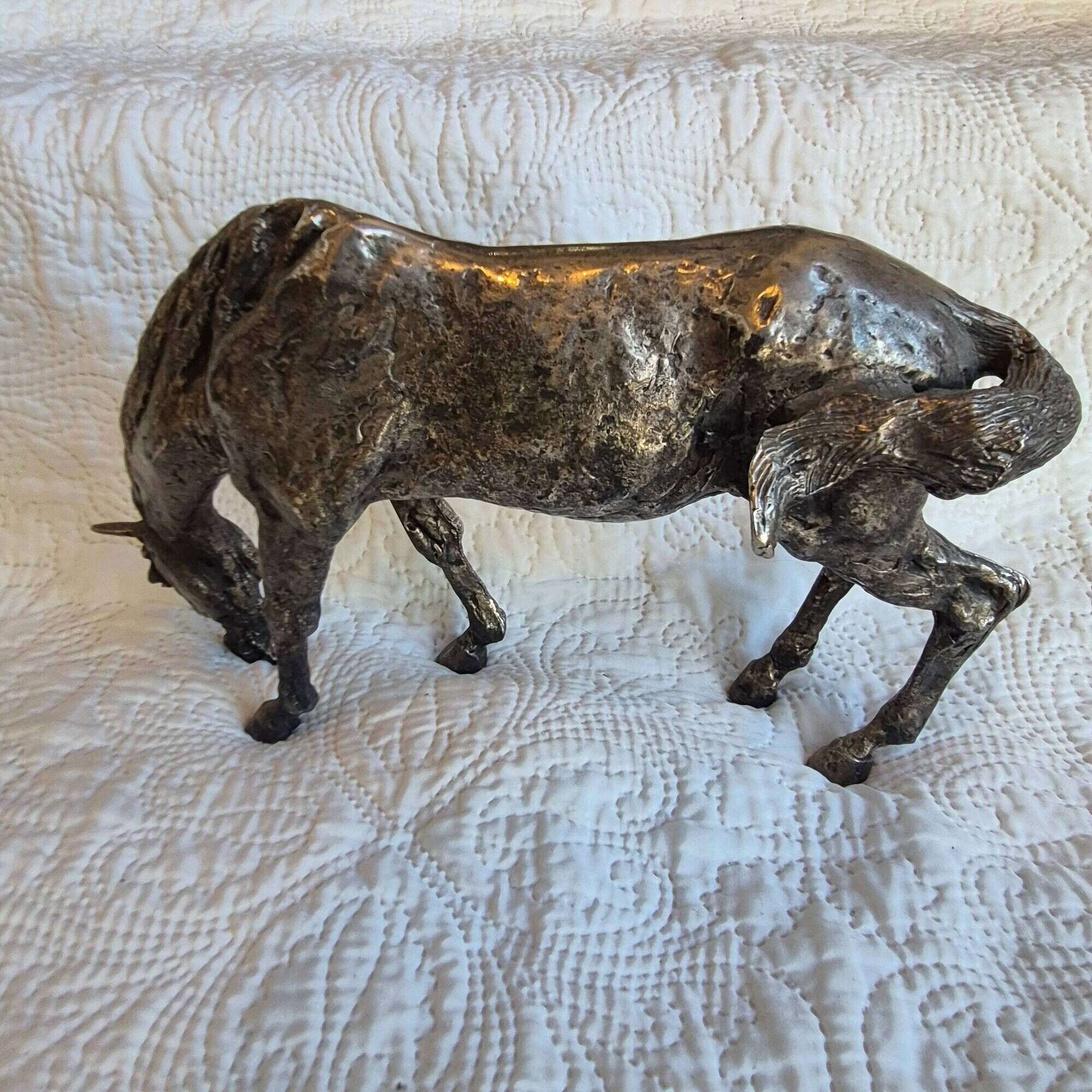 Sculpture of a grazing horse with a silver finish.