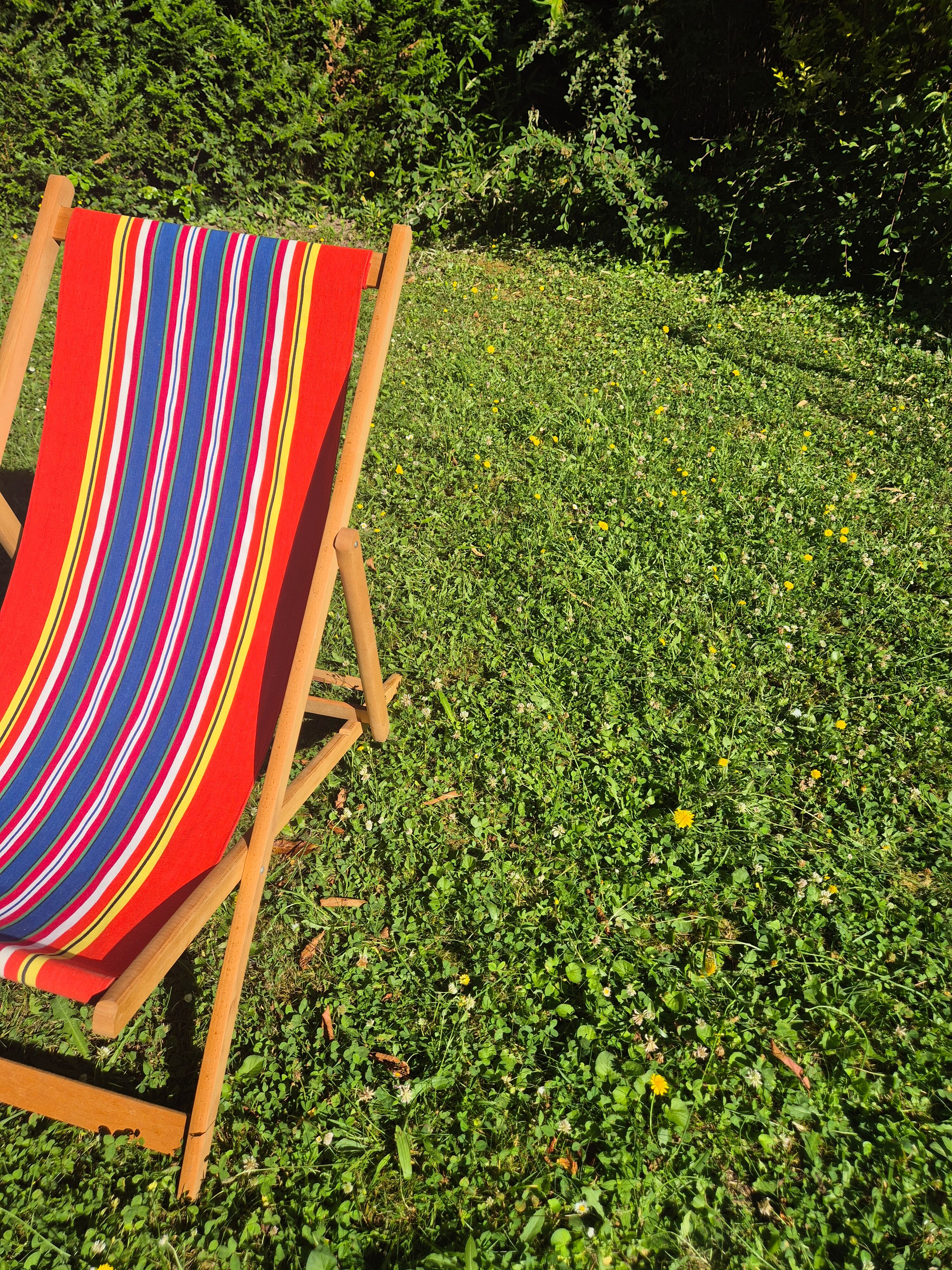 vintage wooden deck chair with red, blue, and yellow striped fabric