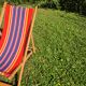 vintage wooden deck chair with red, blue, and yellow striped fabric