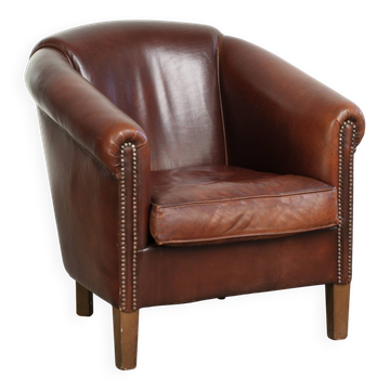 Fauteuil club en peau de mouton au caractère marqué, de couleur cognac foncé, dans le style anglais.