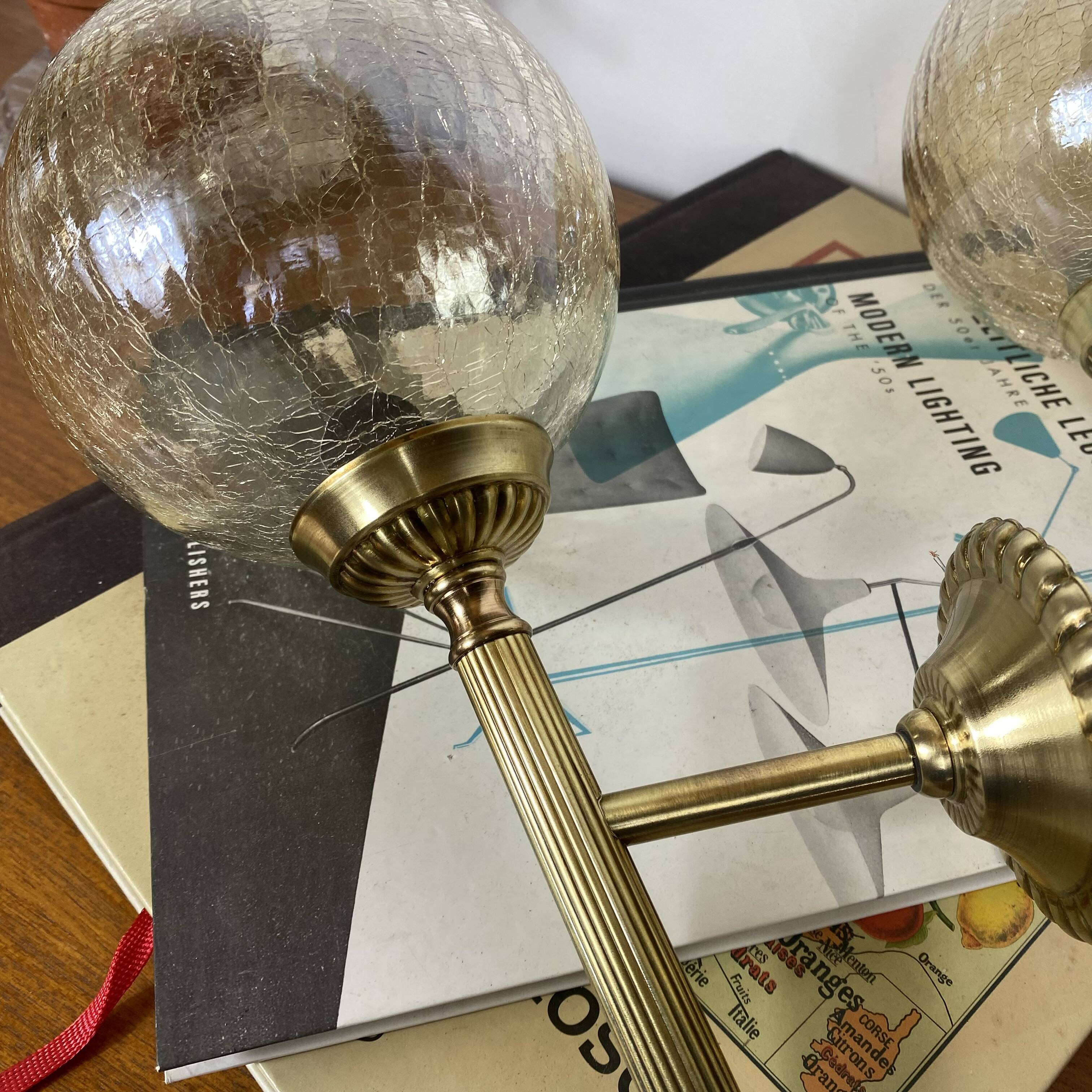 Pair of antique wall sconces torch style brass with glass globes in gold.