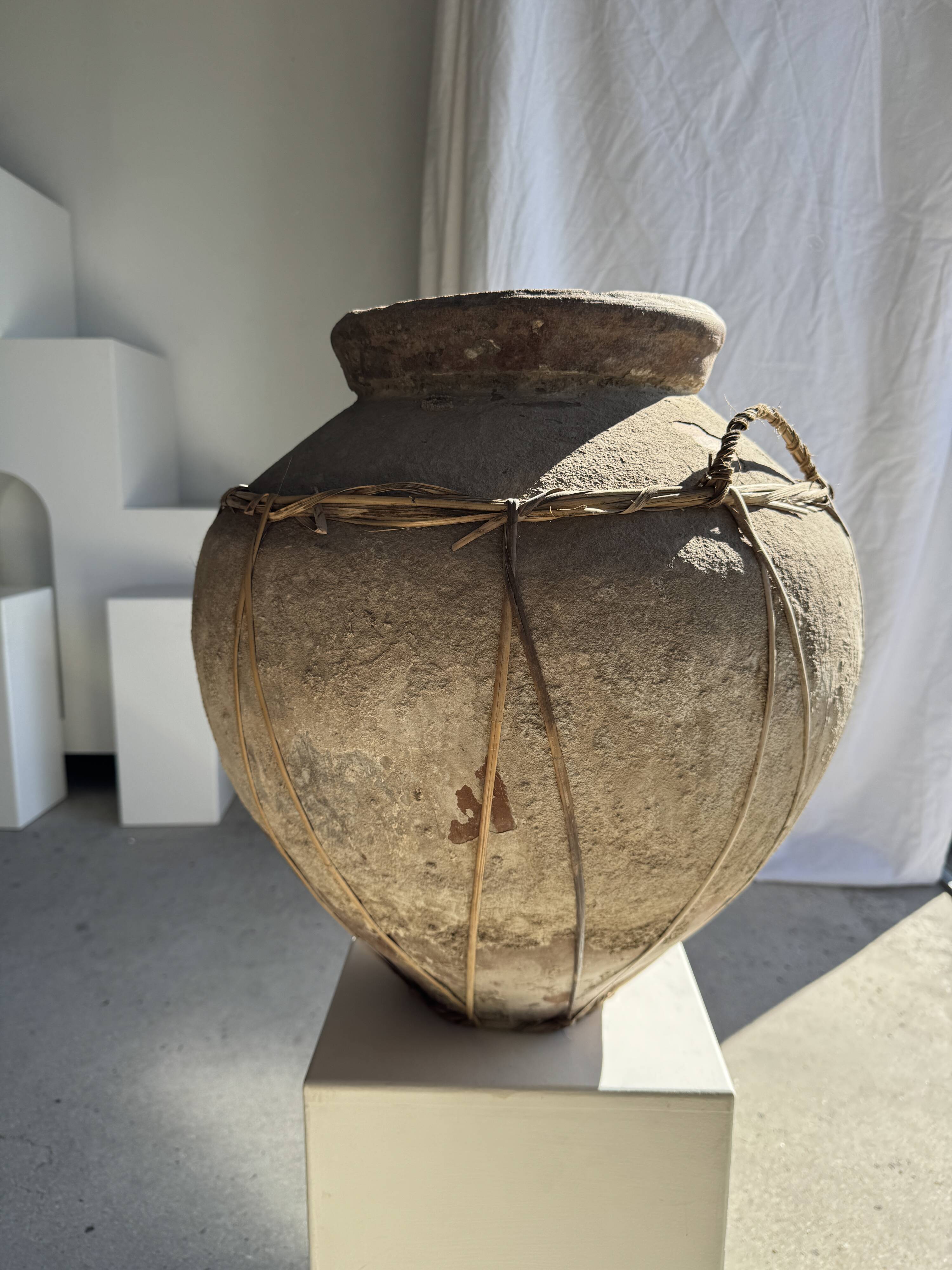 Very large grey and red terracotta pot with handles and rattan crossbars.