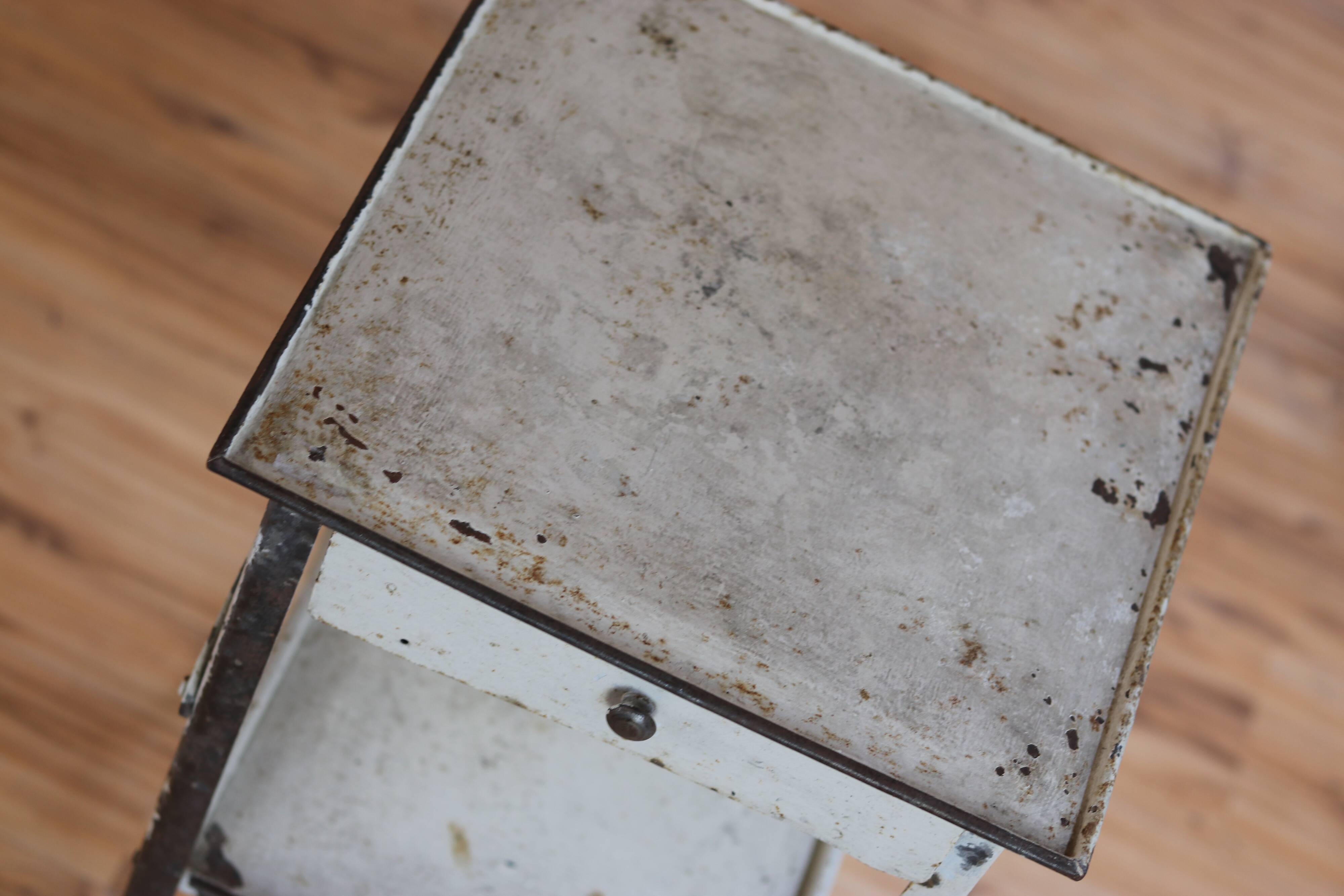Painted metal side table, patinated white, with a drawer and two shelves