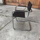 Mid-century round coffee table in chrome and smoked glass with 2 black leather chairs.