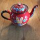 Red enamel teapot with hand-painted floral decoration