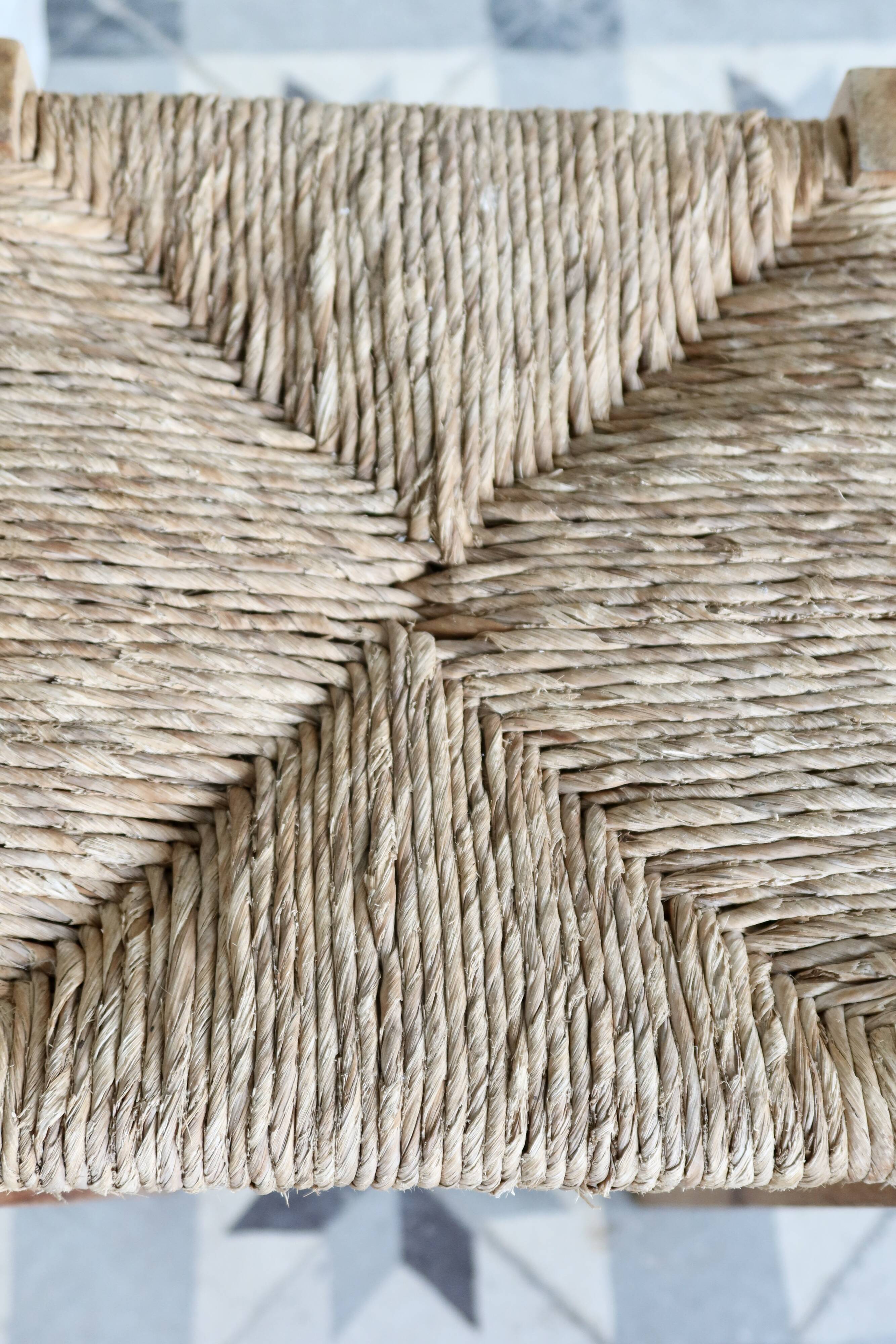 Vintage low stool in rustic style made of wood with a straw seat.