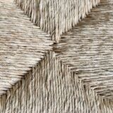 Vintage low stool in rustic style made of wood with a straw seat.