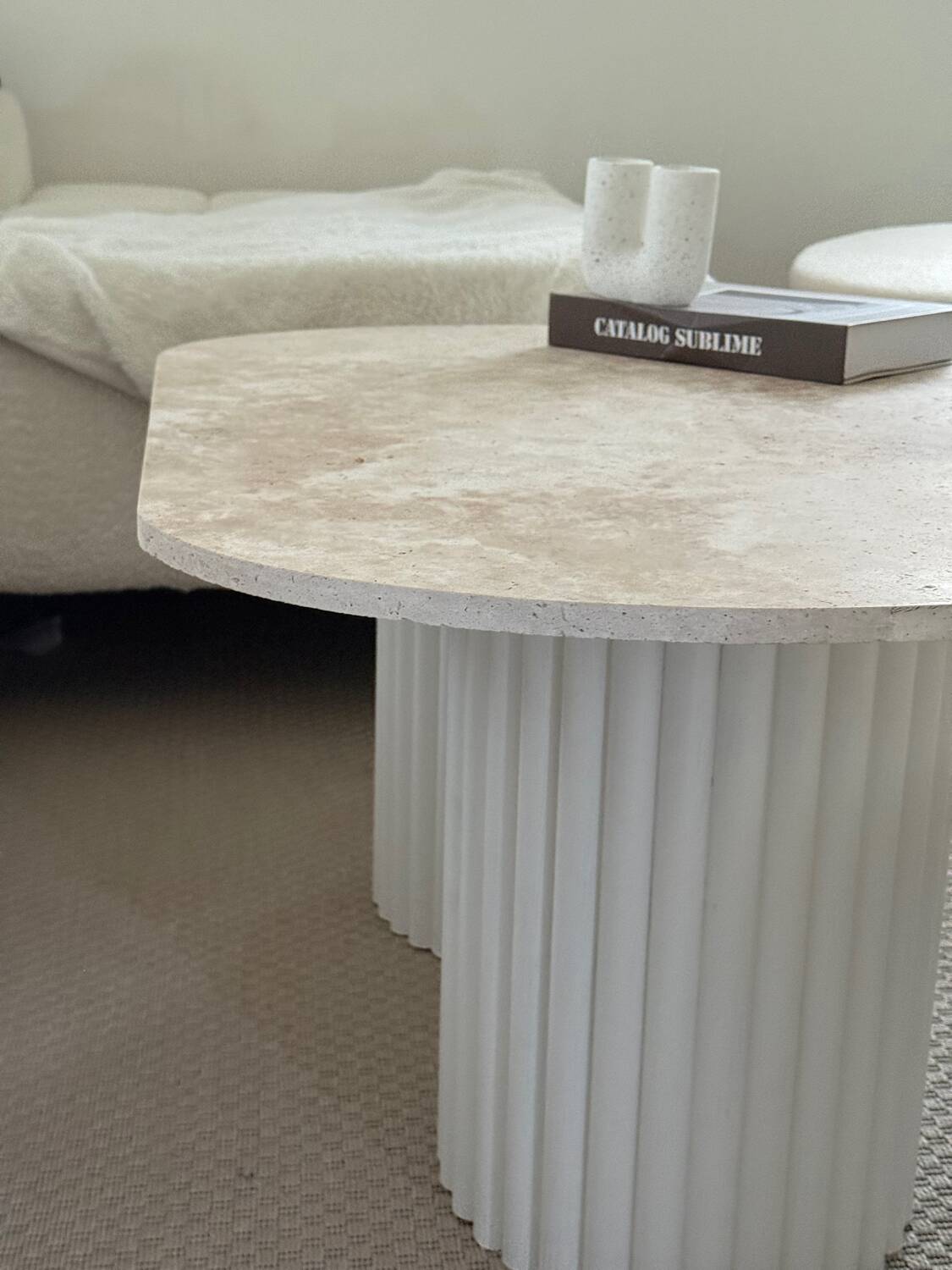 Oval coffee table in travertine and white fluted wood.