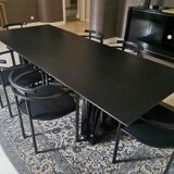 Table de salle à manger noire, en bois, rectangle avec chaises rembourrées.