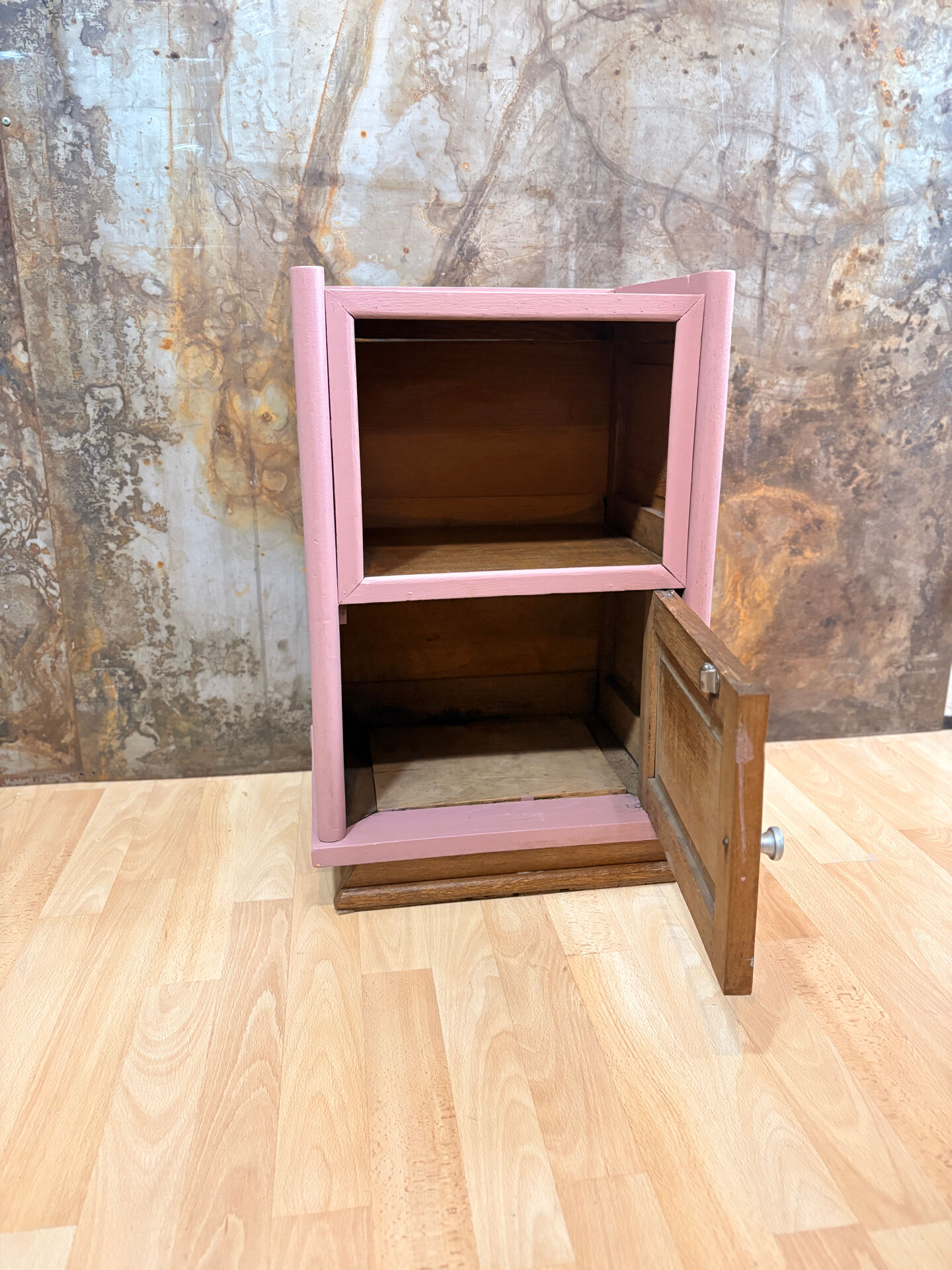 Pink bedside table with haberdashery and raw wood.