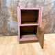 Pink bedside table with haberdashery and raw wood.