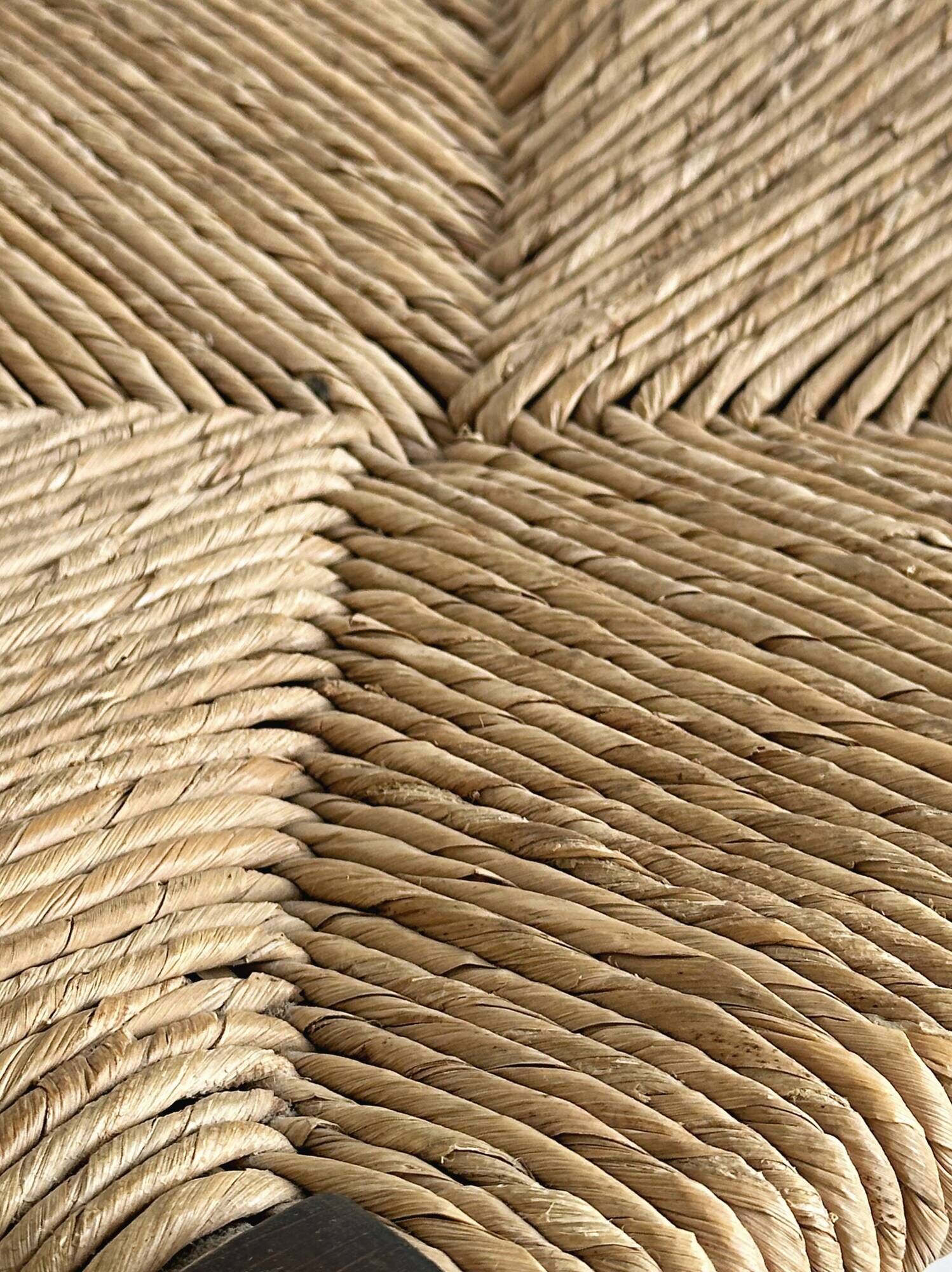 Vintage stool in dark wood with a woven straw seat.