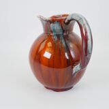 Large red and blue glazed ceramic pitcher signed Delène under the base