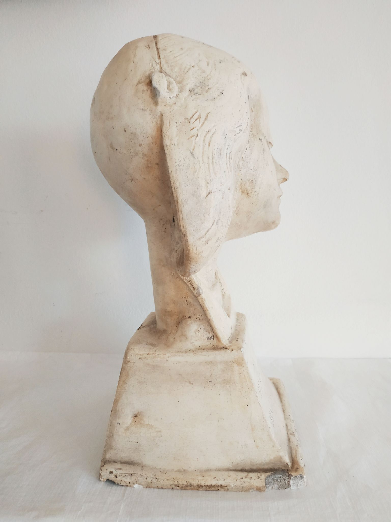 Bust of woman in plaster on pedestal with inscription