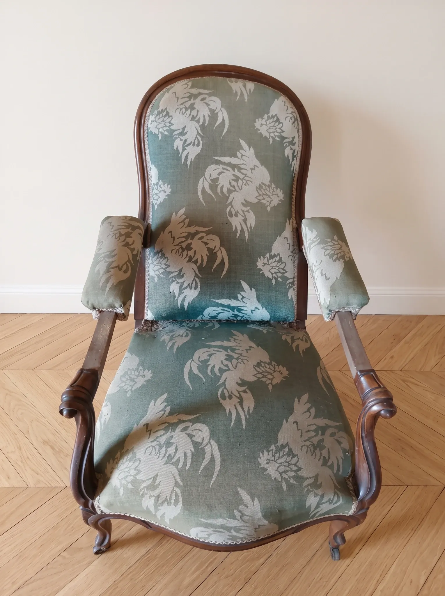 Antique Voltaire armchair in wood and green fabric with floral patterns.