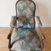Antique Voltaire armchair in wood and green fabric with floral patterns.