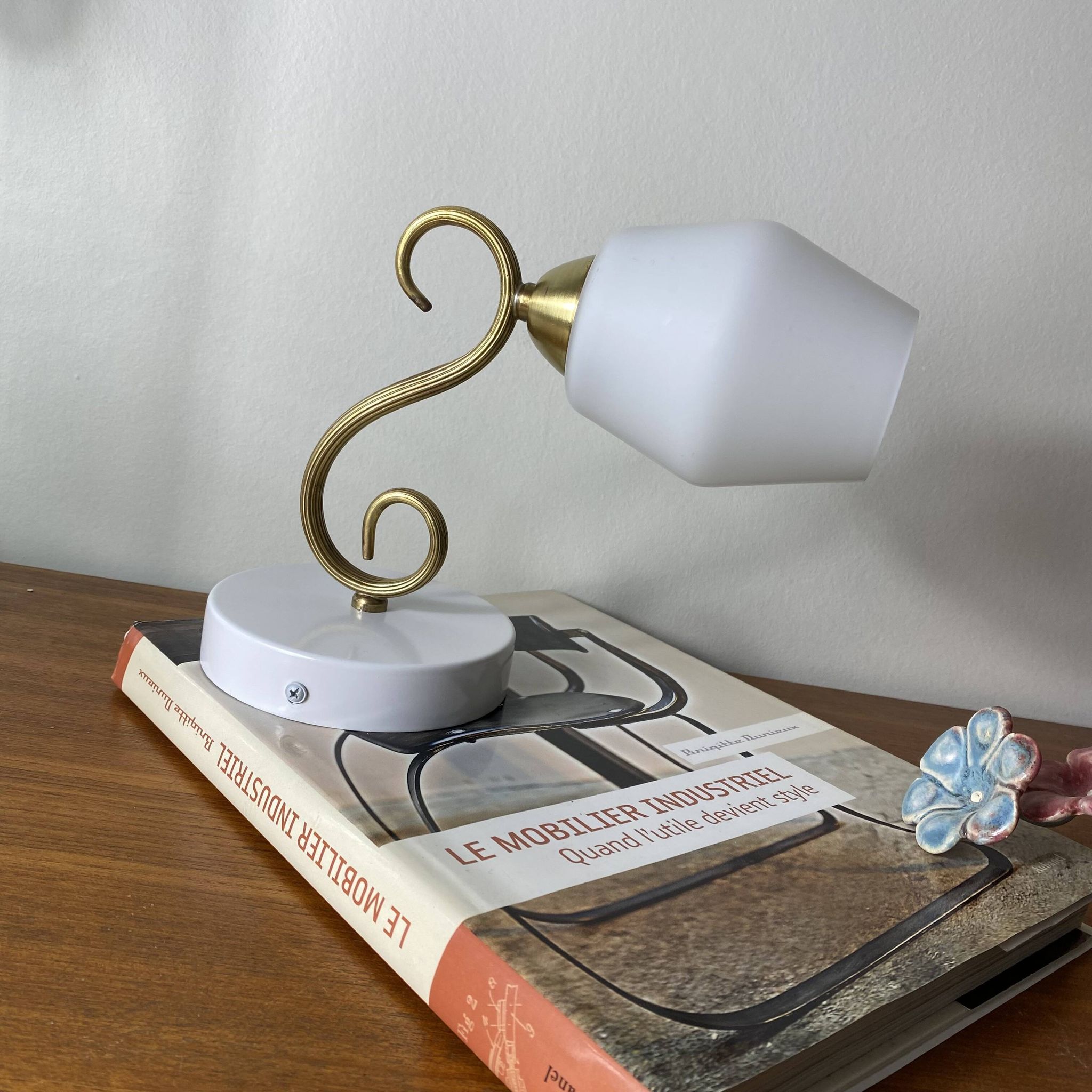 Swan neck wall light in brass with a white glass shade.