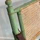 Paire de chaises safari pliantes façon faux-bambou patiné, dossiers et assises cannées et repose-bras en cuir