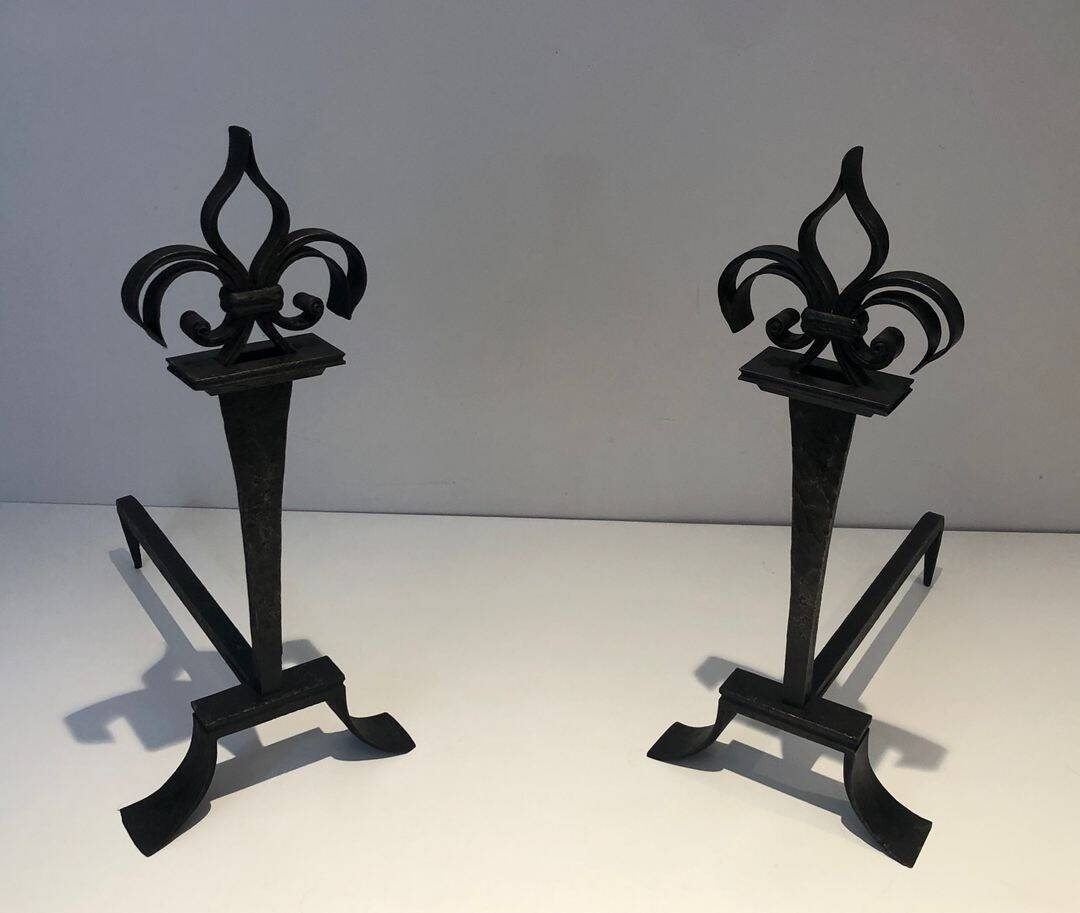 Important pair of wrought iron andirons with torch in heraldic fleur-de-lis design.