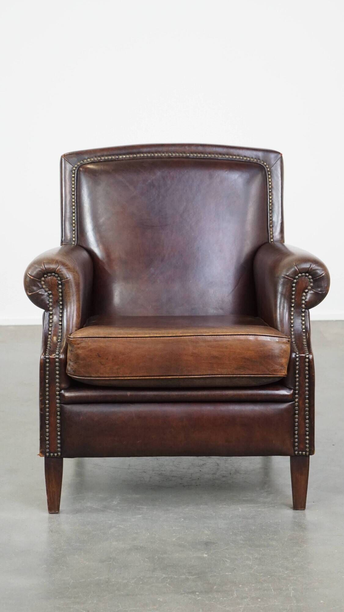 Dark brown sheepskin armchair finished with decorative nails