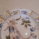 Flat plate in earthenware, hand-painted rural decoration partly in relief,
