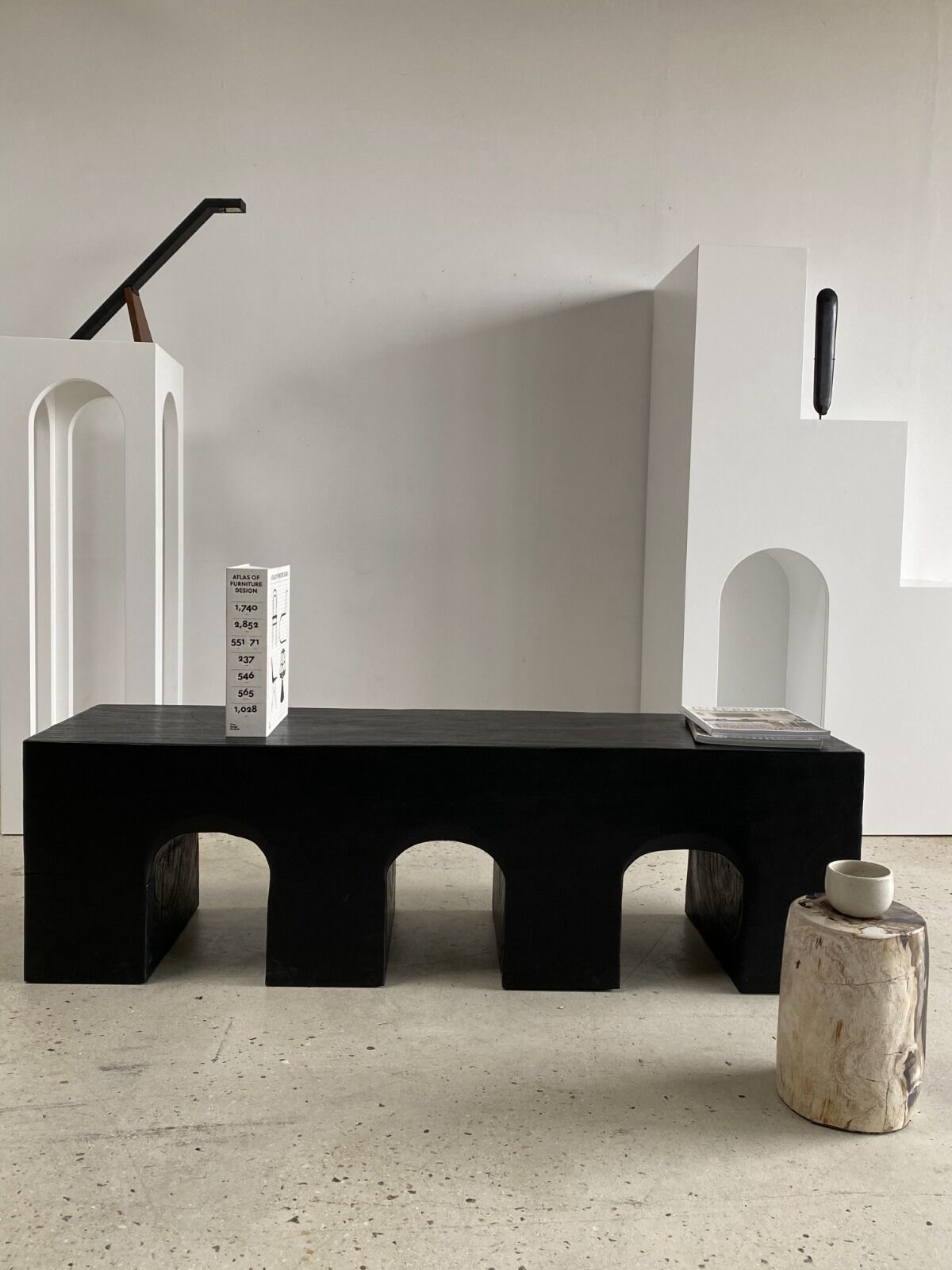 Black solid monoxyl wood bench carved into 3 arches