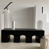 Black solid monoxyl wood bench carved into 3 arches