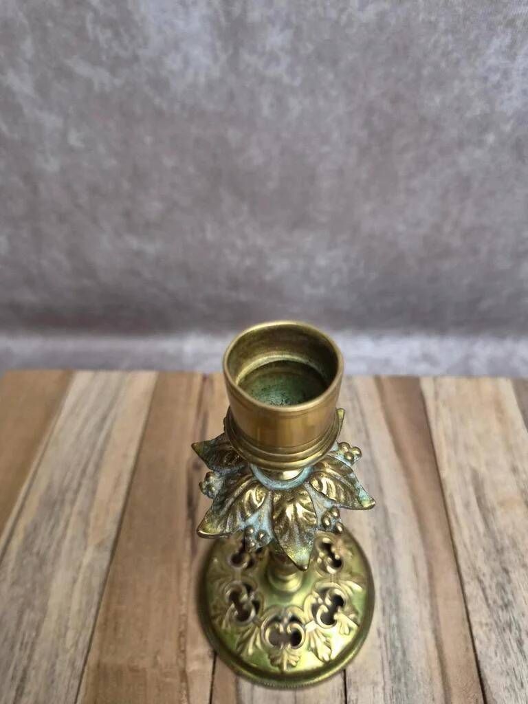 Antique brass candlestick with patina, openwork vintage foliage decoration.