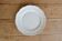 Round vintage ivory earthenware serving dish with scalloped rim.